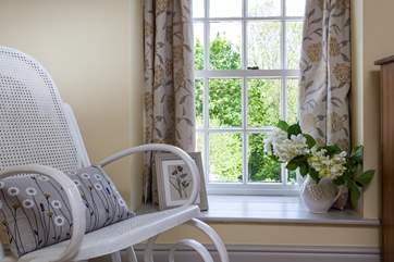 The bedroom is styled beautifully in calming creams and white. Snuggle up on this gorgeous rocking chair, and watch the birds fly past.
