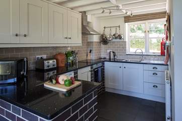 The kitchen is in one corner of the open plan living space and is very well-equipped. The window looks out onto the enclosed rear courtyard.