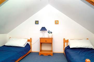 Bedroom 3 has sloping ceilings and is furnished with low single beds.
