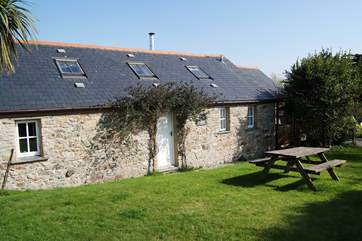 The exterior of the cottage, which has an enclosed lawned garden alongside it.