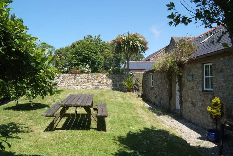 The cottage garden is bordered by mature hedges and shrubs and a lovely stone wall.