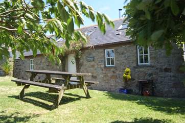 The lawn alongside the cottage is bordered by mature hedges and shrubs.