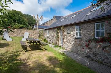 The exterior of the cottage, which has an enclosed lawned garden alongside it.