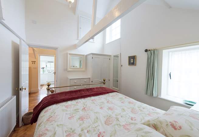 The bedroom shares the high ceiling and light, airy feel of the rest of the cottage.