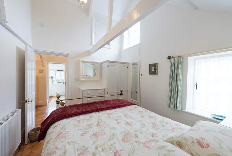 The bedroom shares the high ceiling and light, airy feel of the rest of the cottage.