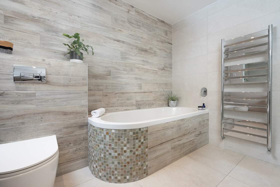 The stylish en suite bathroom tempts unhurried bubble soaked baths after a long day luxuriating on the golden sandy beaches nearby.