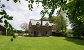 The cottage looks out onto the enclosed garden and has wonderful views, the owner's house is to the right in the background. - Thumbnail Image