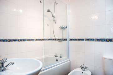 The bathroom is light and airy and has a fitted shower over the bath.