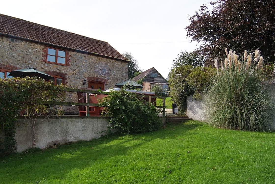 The hot tub is on the terrace with the garden in front.