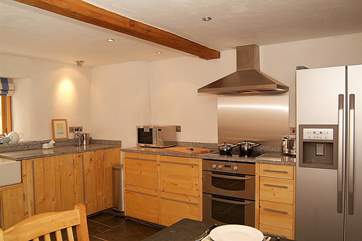 Extremely well-equipped, the kitchen boasts a huge American-style fridge and bespoke wooden kitchen units.