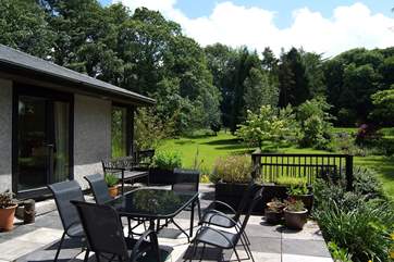 The patio looks out over the large lawn and beautifully planted garden.