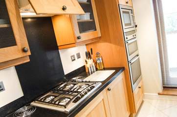 The fully equipped kitchen has gleaming stainless steel appliances with a double oven, built-in microwave and gas hob.