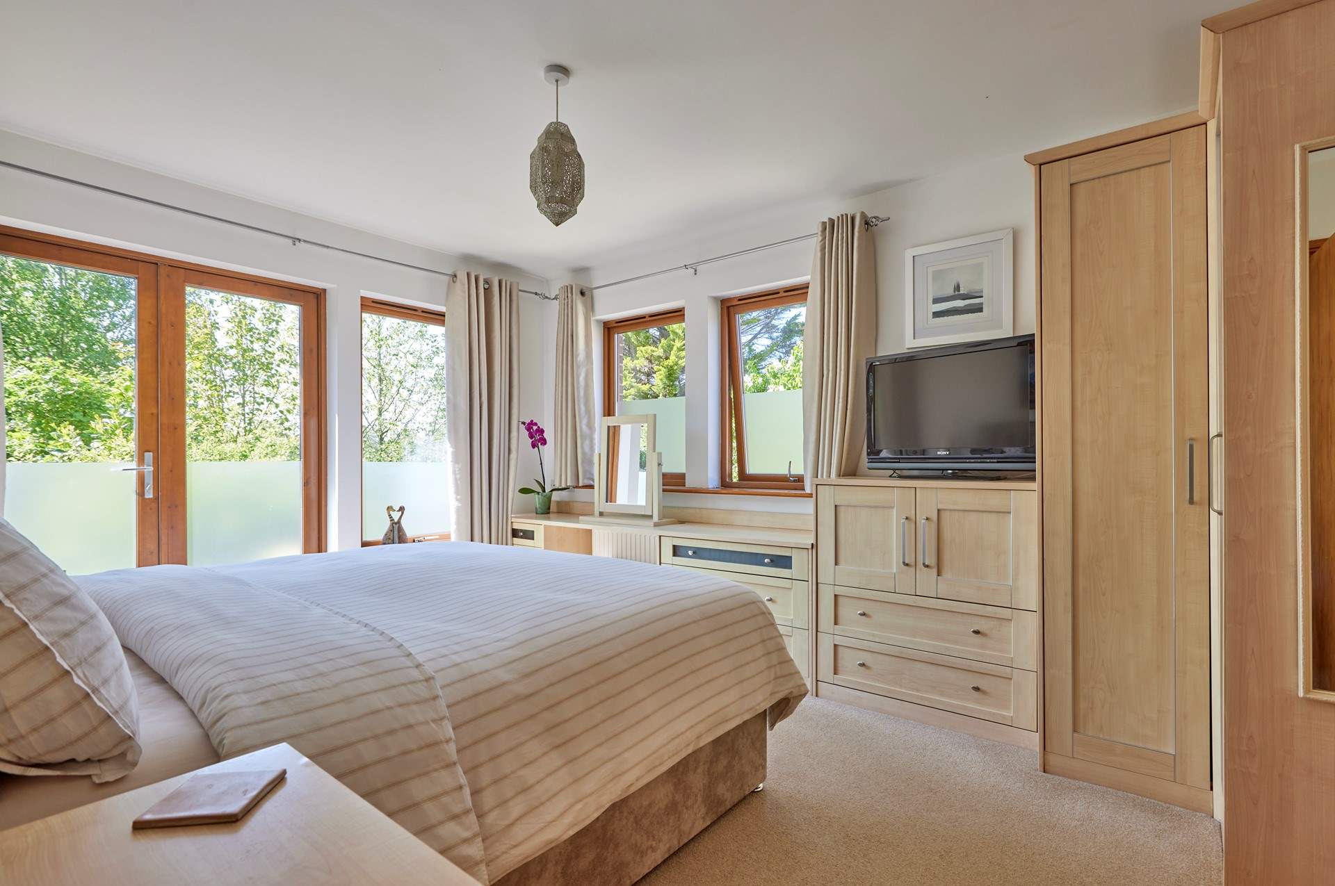 The lovely primary en-suite bedroom has French doors leading out onto the rear terrace and a very tempting super-king (zip and link) bed.