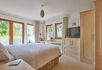 The lovely primary en-suite bedroom has French doors leading out onto the rear terrace and a very tempting super-king (zip and link) bed.