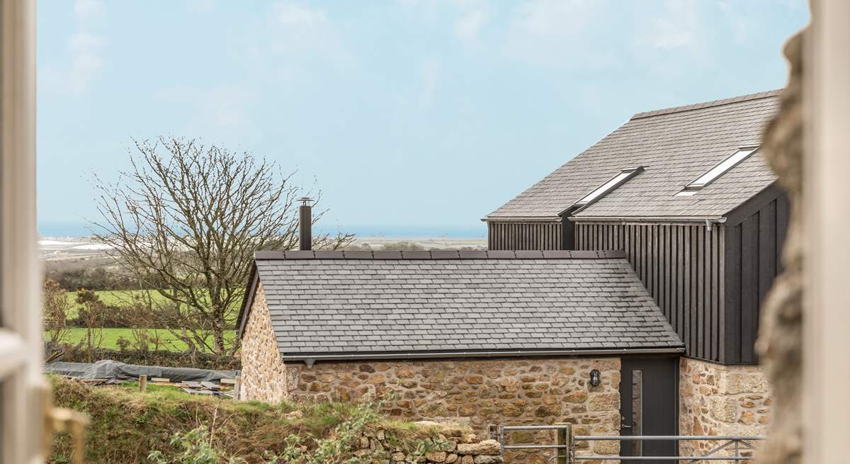 The view out of the kitchen window over a converted barn and to the rolling countryside and sea beyond. 