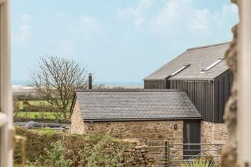 The view out of the kitchen window over a converted barn and to the rolling countryside and sea beyond.