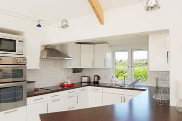 The white high gloss kitchen is beautifully fitted and well-equipped.