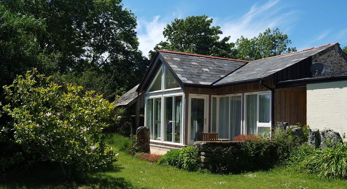 The timber-framed glass wall of the south-facing open plan living-room in Snuggledown, gives views over the fields and woods of Trevethey Farm.