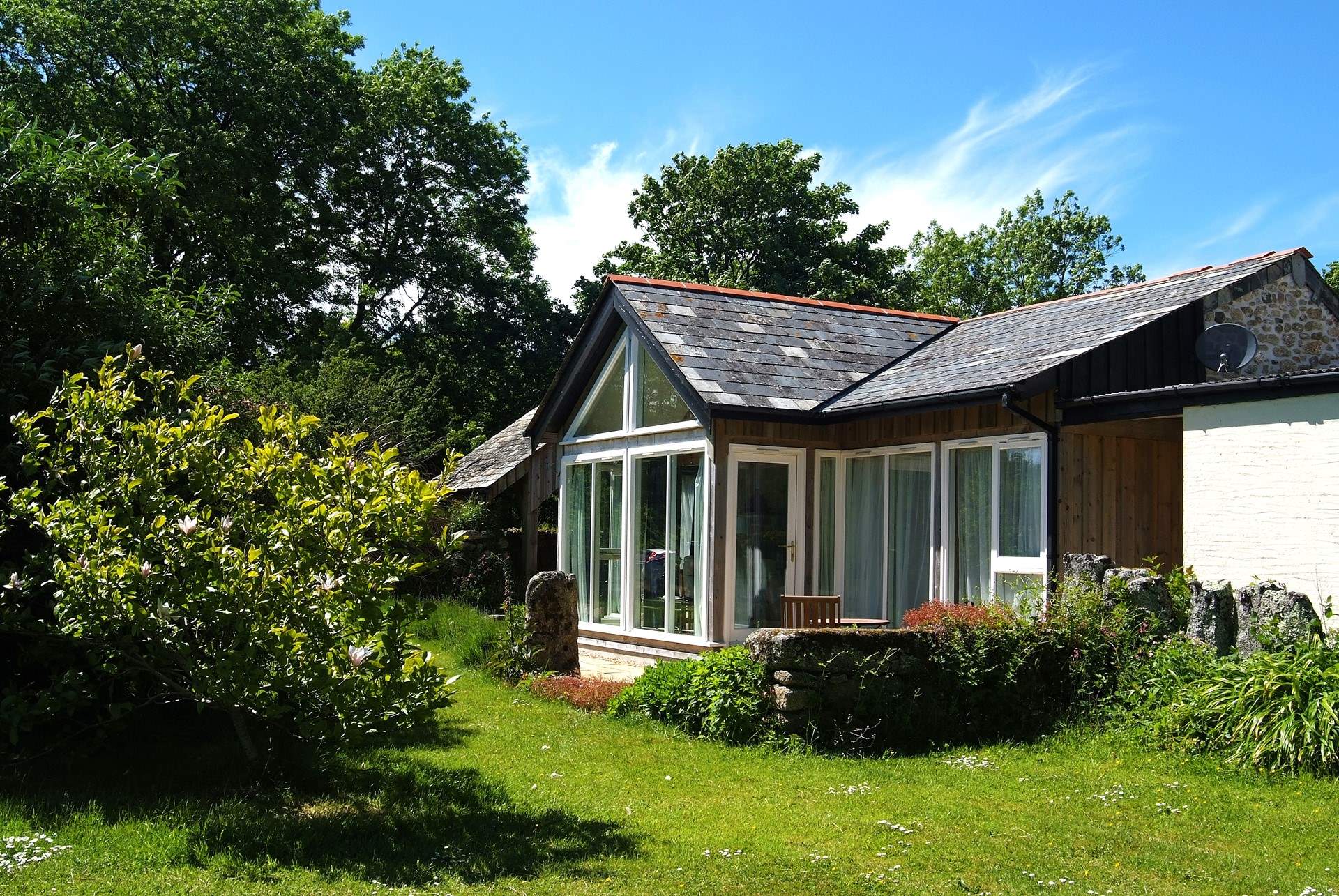The timber-framed glass wall of the south-facing open plan living-room in Snuggledown, gives views over the fields and woods of Trevethey Farm.