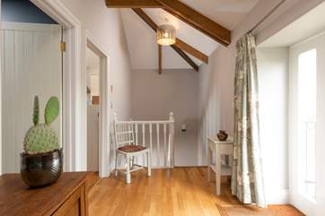The entrance hall with doors to the shower room and kitchen on your left, the sitting room behind you and stairs leading down to the bedrooms.