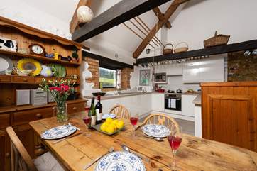 There is a farmhouse style dining-table next to the kitchen-area.