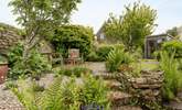 The pretty enclosed back garden with its manicured lawn and attractive flowerbeds. - Thumbnail Image