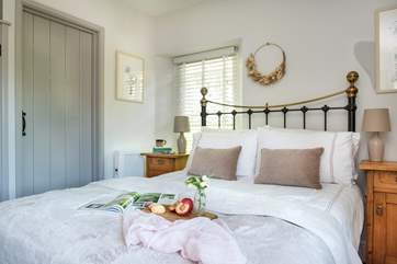 The bedroom has lovely linens and a gorgeous bedstead.
