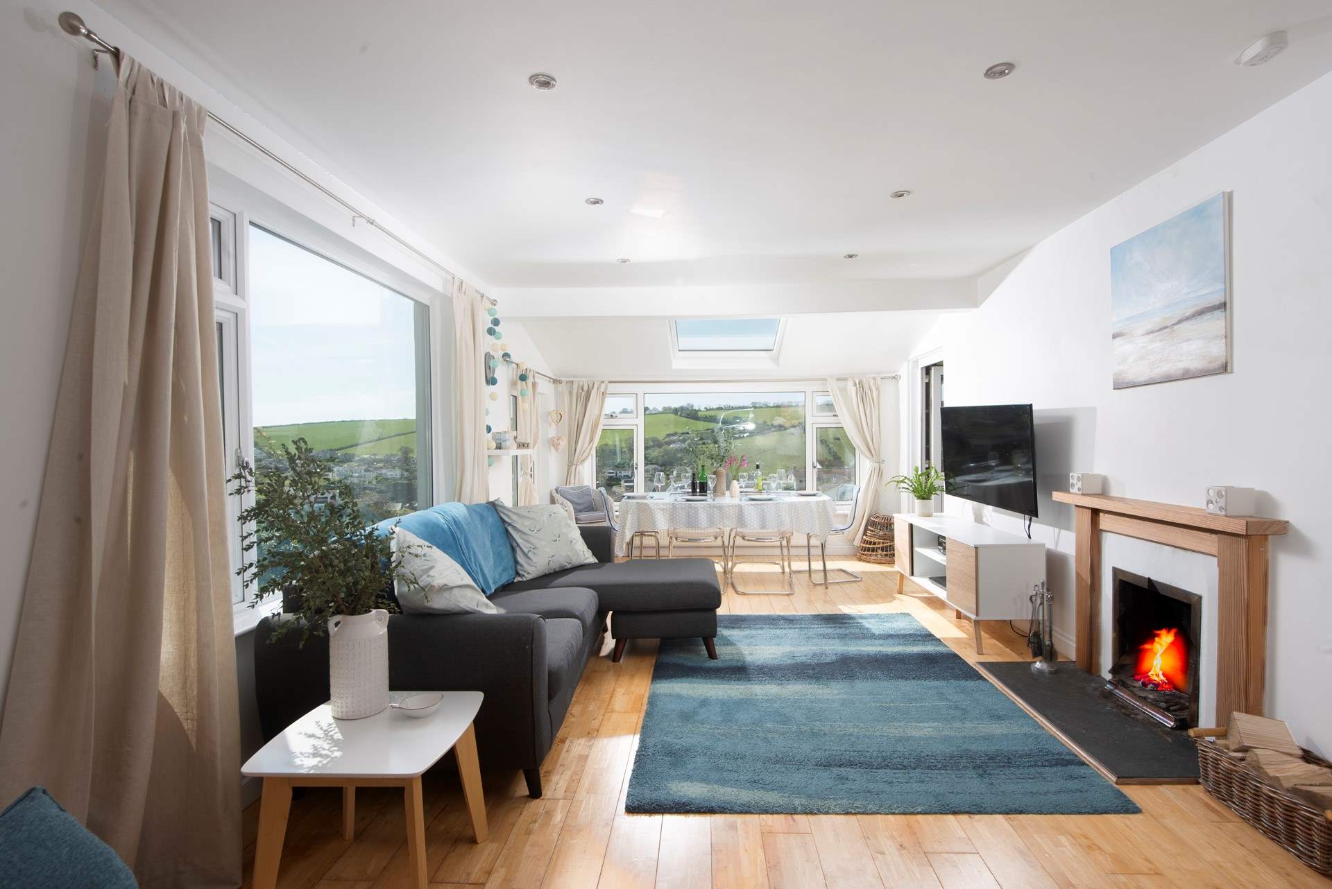 The open plan living-room is flooded with light from the large picture windows.