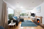 The open plan living-room is flooded with light from the large picture windows.