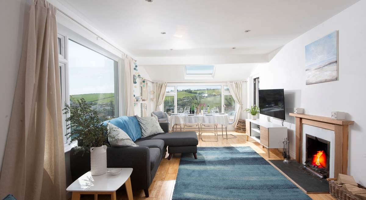 The open plan living-room is flooded with light from the large picture windows.