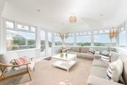 The sunny conservatory end of the sitting-room with double doors leading out to the decking and garden.