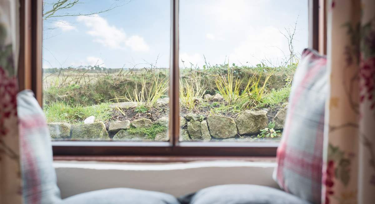 The sitting/dining-room looks out across the enclosed front courtyard to the fields and reservoir beyond.