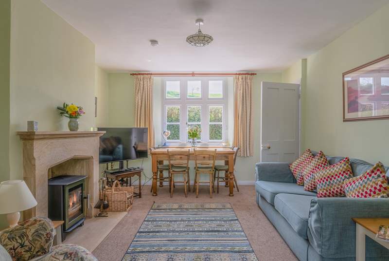 The open plan sitting/dining-room has a beautiful hamstone fireplace and cosy wood-burner.