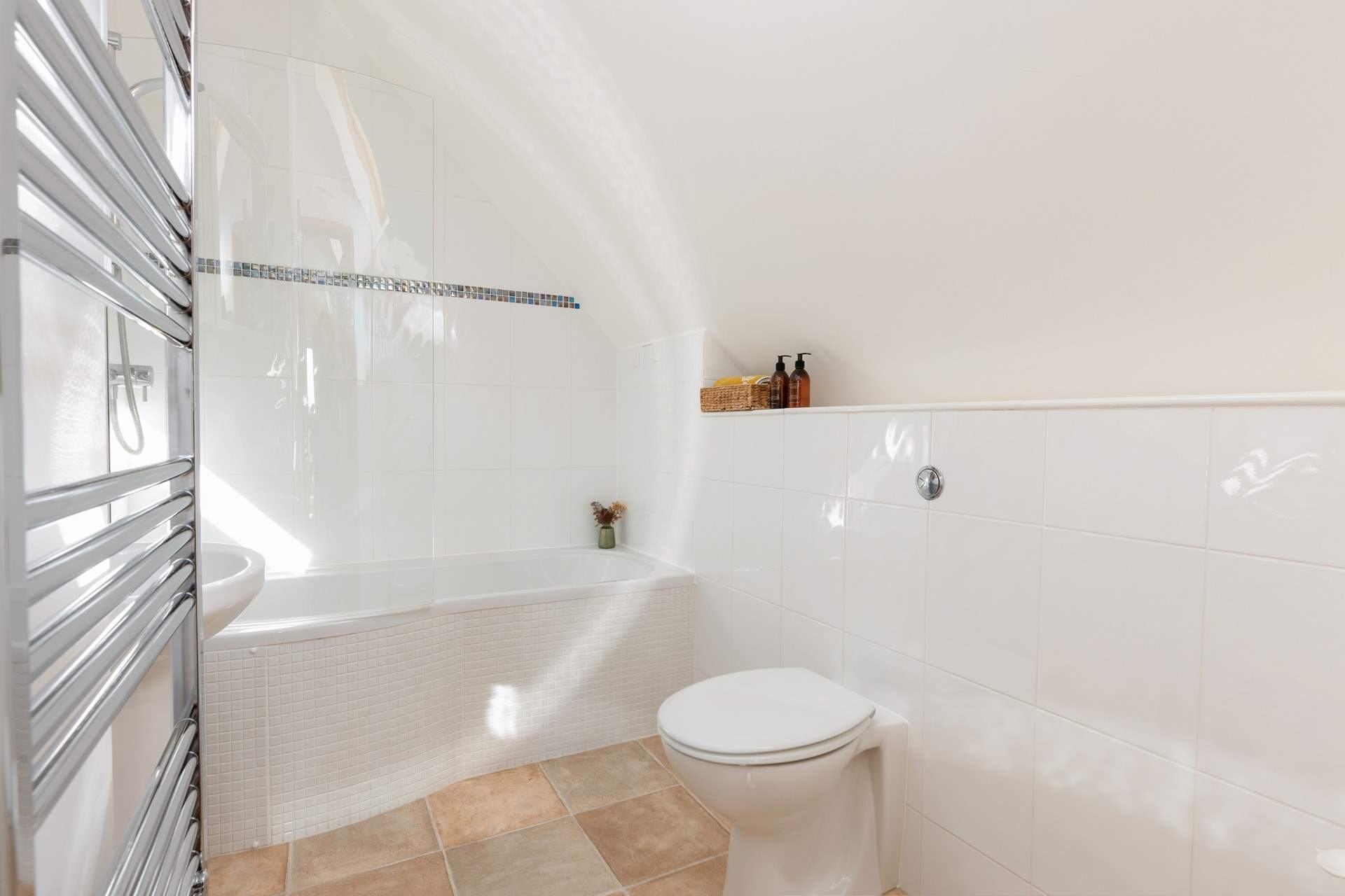 The modern bathroom has a bath with shower over.