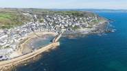 An aerial view of the charming village of Mousehole, the beach is directly in front of the cottage.