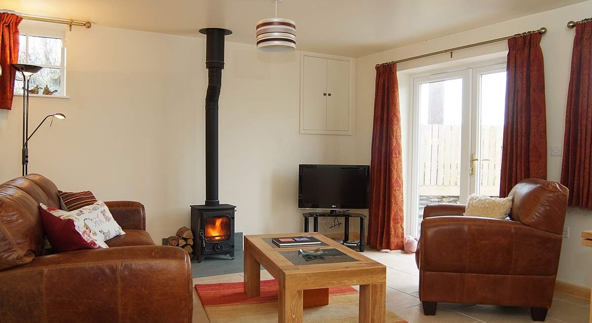 Wheel Barn has a comfortable open plan living-room with a wood-burner and French doors out to an enclosed garden.