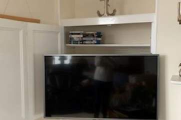 The large television is tucked away in the white cupboard in the far right cupboard in the sitting-room.