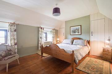 The spacious double bedroom looks out across the fields behind the cottage.