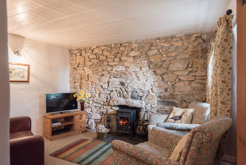 The cosy sitting-room is furnished with two comfy armchairs and a sofa around the wood-burner.