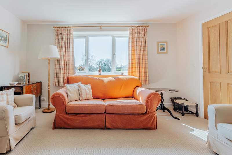 The sitting-room has comfortable sofas and looks out over the garden and open countryside.
