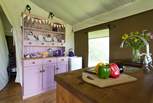 The pink dresser is home to all your crockery and cutlery and is next to the full size fridge.