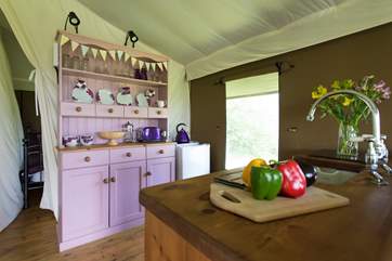 The pink dresser is home to all your crockery and cutlery and is next to the full size fridge.