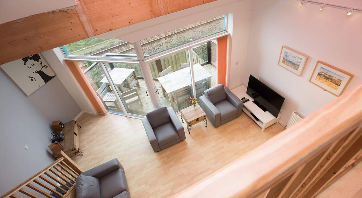 The floor to ceiling doors and windows allow the light to flood into the open plan living-room and mezzanine level above.