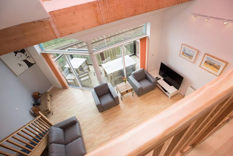 The floor to ceiling doors and windows allow the light to flood into the open plan living-room and mezzanine level above.