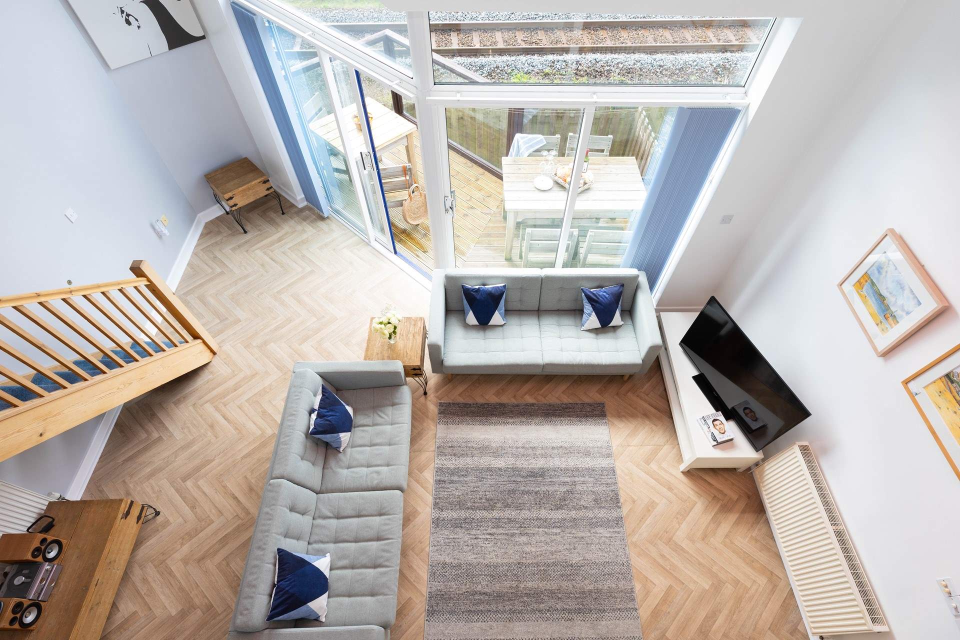 Looking down from the mezzanine you can see the spacious open plan downstairs living area and the upper level terrace with outdoor seating.