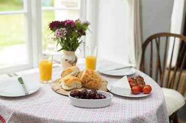 The dining-table sits in front of a pretty cottage window looking out over the garden.