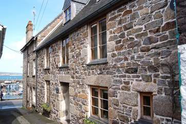 The pretty exterior of Rubble Cottage with the harbour in the background.