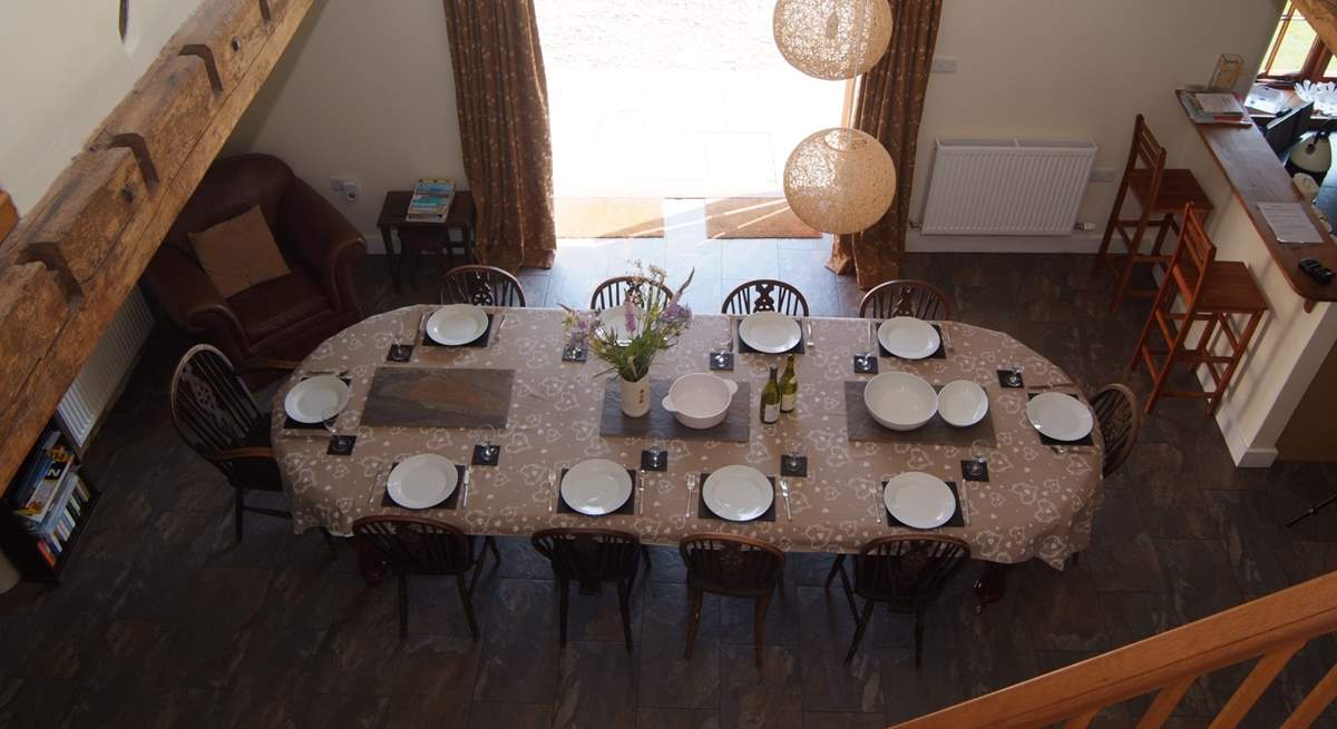 The spacious open plan living-area has the dining-table in the central part, the living-room to the left and the kitchen to the right.