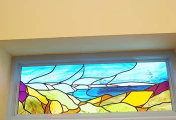 The stained glass window in the bedroom is beauitful, reflecting the stunning coastline outside.