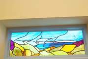 The stained glass window in the bedroom is beauitful, reflecting the stunning coastline outside.